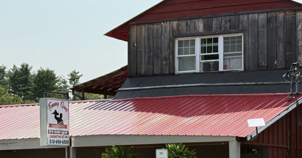 Tommy Guns Pizzeria in Warrensburg, NY — red barn-style building with the Tommy Guns blade sign, patio seating, and a Starlink dish installed by Adaptive IT